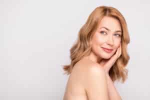 A woman touching her cheek showing the results of Celluma therapy